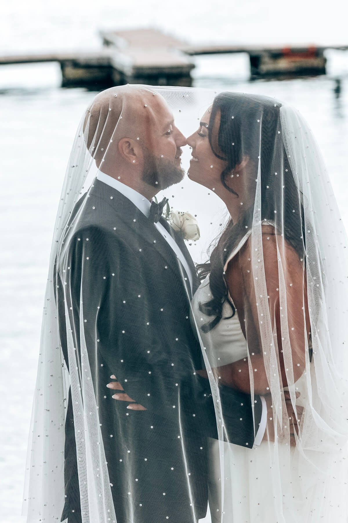 Bride and groom almost kissing under the veil